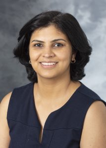 Woman with shoulder-length dark hair wearing a dark sleeveless blouse